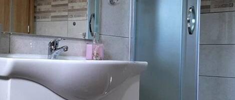 A bathroom with a white vanity, a sink, a mirror, and a glass shower enclosure.