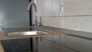 A modern kitchen with a built-in stovetop and a stainless steel sink. - Apartment Sime (Vrsi)