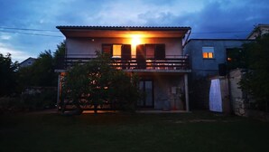 A two-story house with a balcony, a small front porch, and a visible garage. - Apartment Maria (Pirovac)