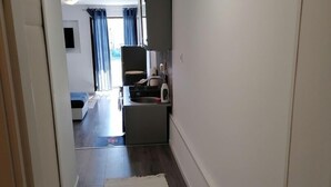 A narrow hallway with a wooden floor, a white rug, and a kitchenette area with a microwave and small cabinets. - Apartment Maria (Pirovac)