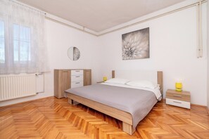 A bedroom with a bed, bedside tables, a mirror, and a radiator. - Apartment Lilac (Trogir)