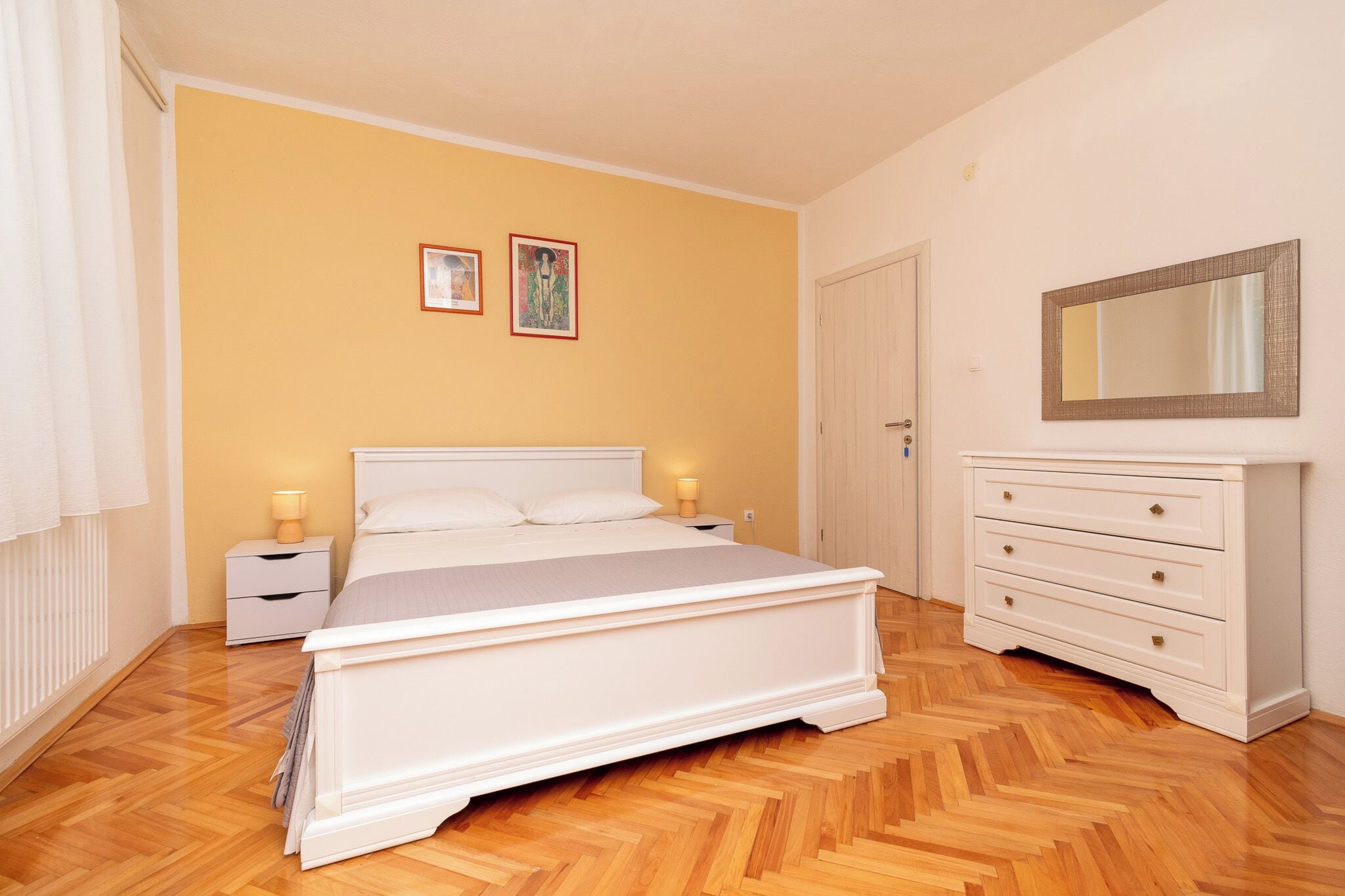 Une chambre à coucher comprenant un lit, des tables de chevet, une commode et un miroir.