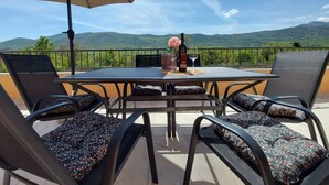Eine Terrasse mit Tisch, Stühlen und Sonnenschirm.