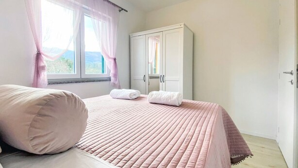 A bedroom with a bed, a wardrobe, and a window with curtains. - Villa Vinka (Vrgorac)