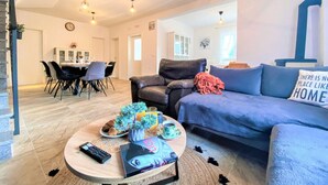 Ein modernes Wohnzimmer mit einer Couch, einem Couchtisch und einem Essbereich im Hintergrund.