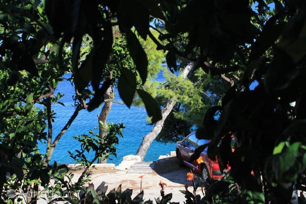 Une voiture est garée au bord d’une route côtière, offrant une vue dégagée sur la mer.