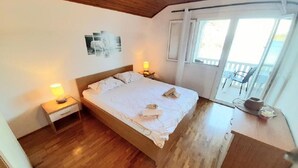 Une chambre avec un lit en bois, des tables de chevet avec des lampes, une fenêtre avec des rideaux et une vue sur le balcon.