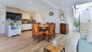 Un'ampia zona giorno con tavolo da pranzo, sedie, divano e una scala che conduce a un piano superiore.