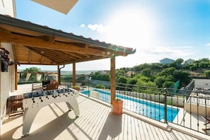 A poolside area with a foosball table, outdoor seating, and a view of a swimming pool and surrounding landscape. - House Kate (Benkovac)