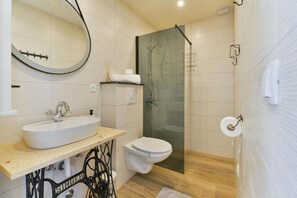 A modern bathroom with a freestanding sink, toilet, and glass shower enclosure. - House Kate (Benkovac)