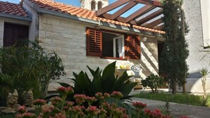 A house with a stone facade, a tiled roof, and a wooden balcony. - House Ivi (Supetar)