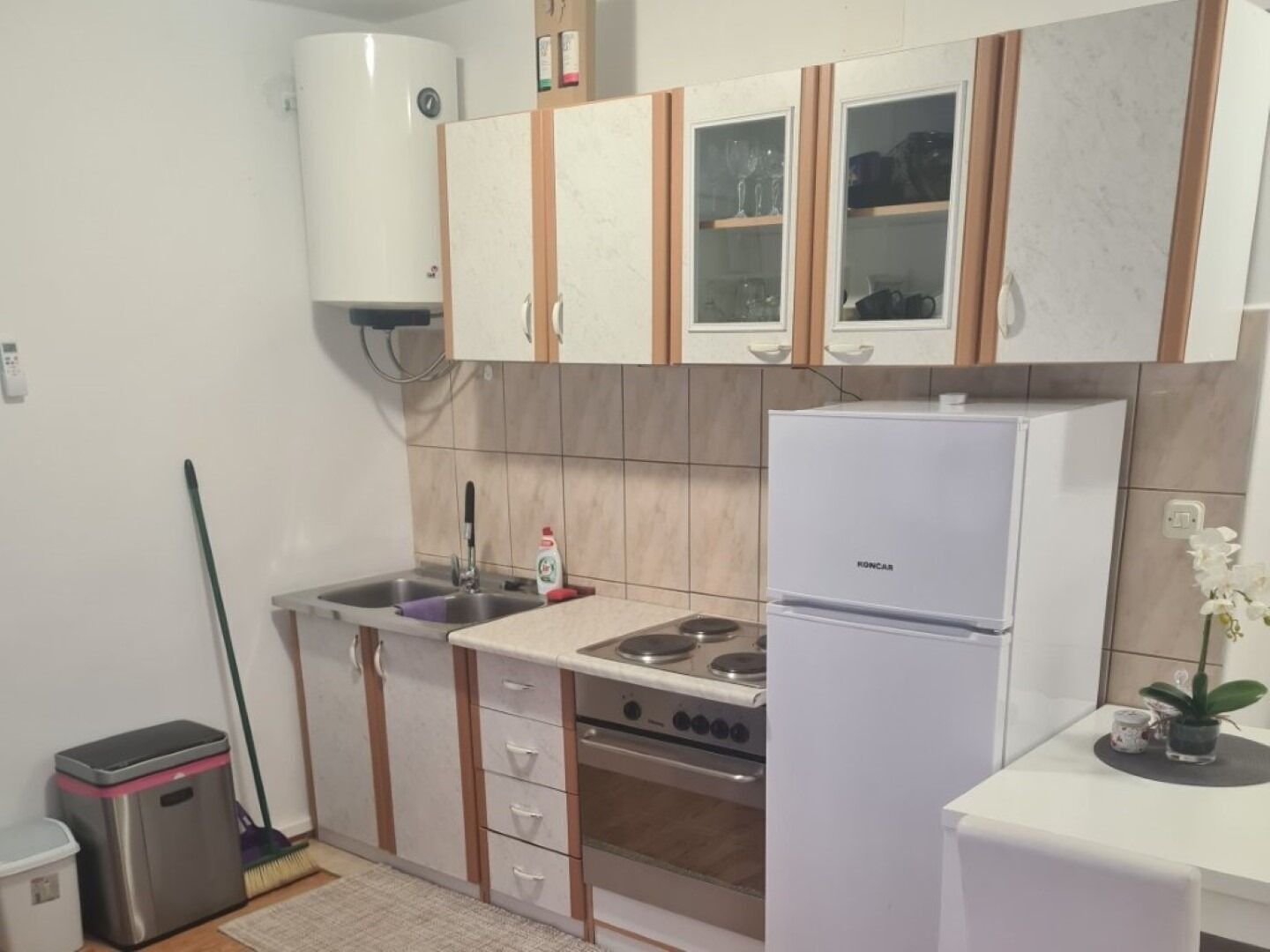 A compact kitchen with a built-in stove, a refrigerator, and cabinets with glass doors.