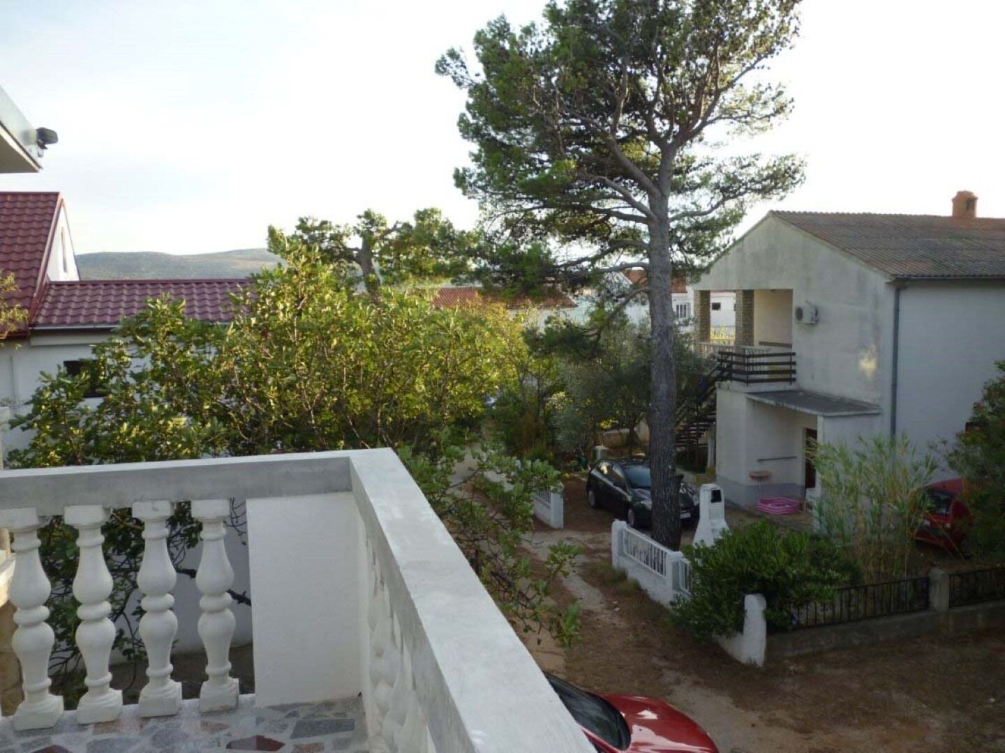 A residential area with a white building featuring a balcony and a staircase.