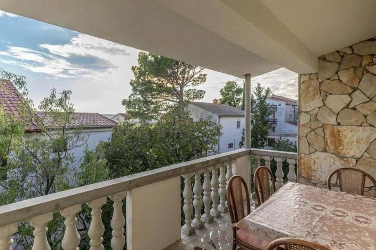 A balcony with a stone wall, a tiled floor, and a table with chairs.