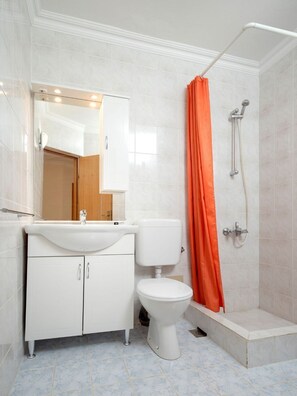 A bathroom with a white sink, toilet, and shower. - Apartments Josi (Jelsa)
