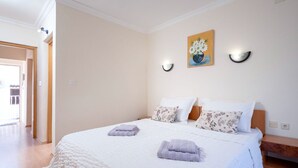 A bedroom with a large bed, two bedside tables, a painting on the wall, and a door leading to another room. - Apartments Josi (Jelsa)