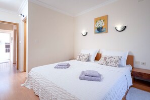 A bedroom with a large bed, two bedside tables, a painting on the wall, and a door leading to another room. - Apartments Josi (Jelsa)