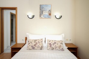 A bedroom with a bed, two wall-mounted nightstands, a nightlight, and a painting on the wall. - Apartments Josi (Jelsa)