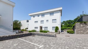 Ein modernes Gebäude mit flachem Dach, zahlreichen Fenstern und einem gepflasterten Innenhof.