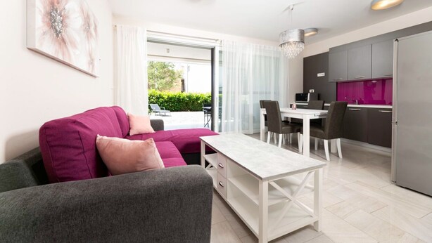 Ein modernes Wohnzimmer mit einer Couch, einem Esstisch und einer Küchenzeile.