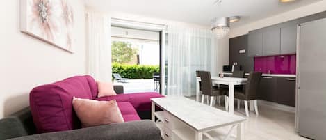 A modern living room with a sofa, a dining table, and a kitchen area.