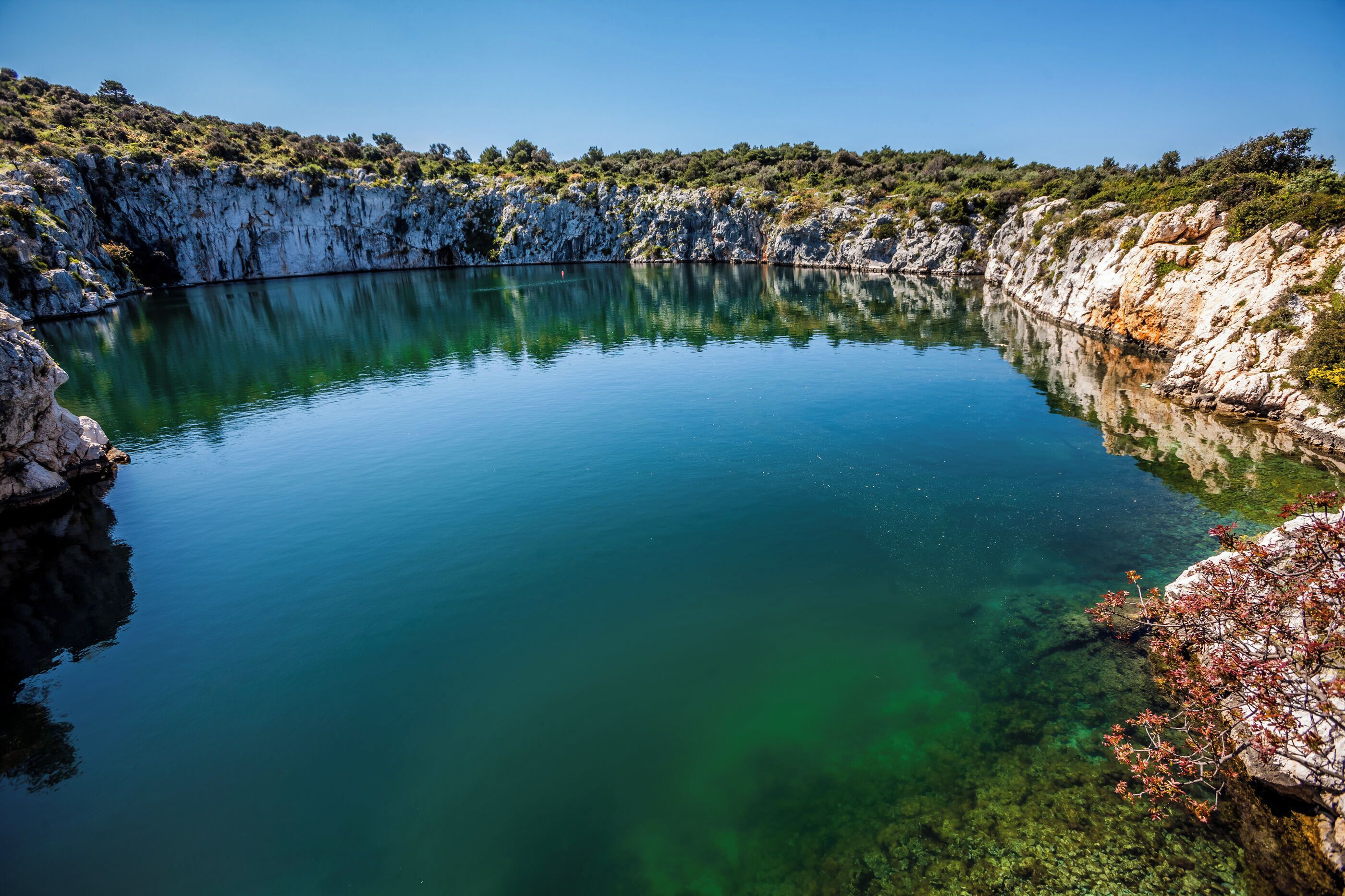Um lago calmo rodeado por penhascos rochosos com vegetação escassa.