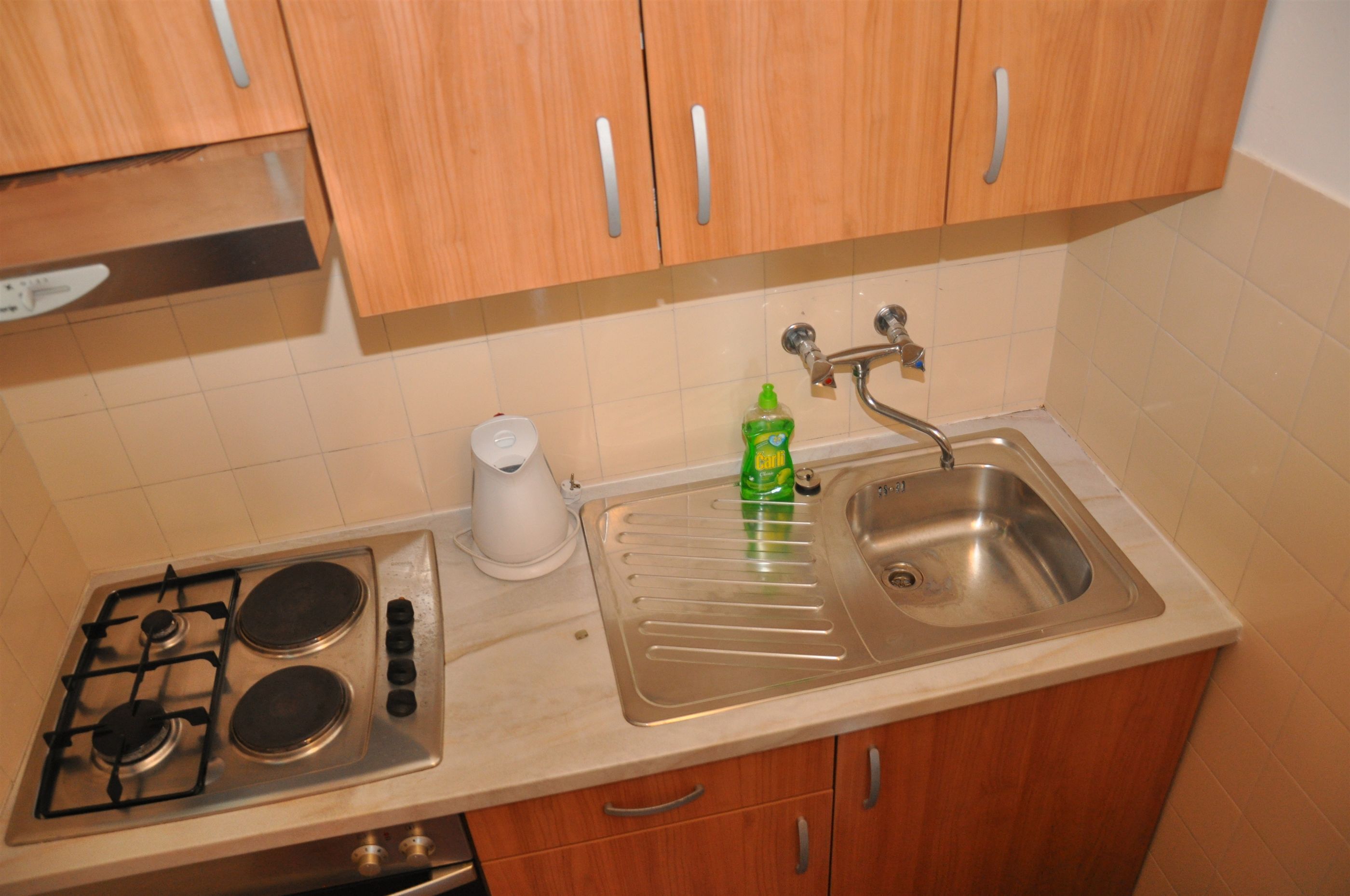 A kitchen with wooden cabinets, a stainless steel sink, and a gas stove.