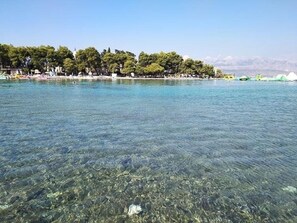 On aperçoit clairement un lac, avec une rive bordée d’arbres et une chaîne de montagnes à l’horizon.