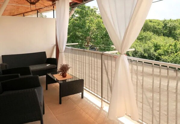 Un balcon avec un canapé, une petite table et une plante en pot.
