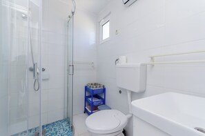 Une salle de bain avec des toilettes, une douche et une petite fenêtre.