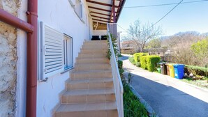 Ein Haus mit überdachter Veranda, einer Treppe, die zu einer Tür führt, und blauem Himmel.
