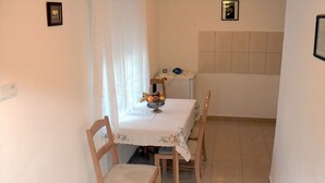 Ein Essbereich mit Tisch und vier Stühlen, einer Obstschale sowie einem kleinen Tisch mit Globus und einem gerahmten Bild an der Wand.