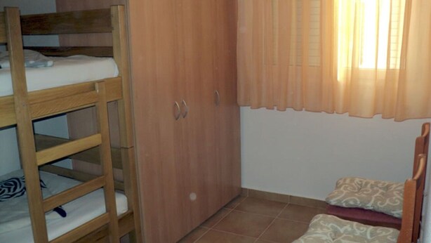Ein Zimmer mit einem Etagenbett, einem Holzschrank und einem kleinen Bett mit gemusterten Bettbezügen.