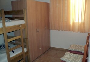 A room with a bunk bed, wooden wardrobe, and a small bed with patterned bedding. - Apartments Niko (Benkovac)