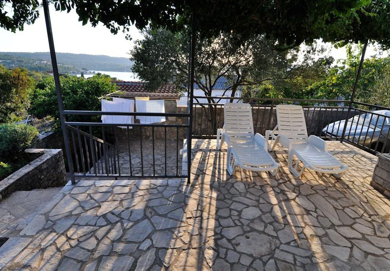 A stone patio with outdoor seating and a view of the sea.