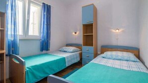Une chambre avec deux lits simples, une armoire et une fenêtre avec des rideaux.
