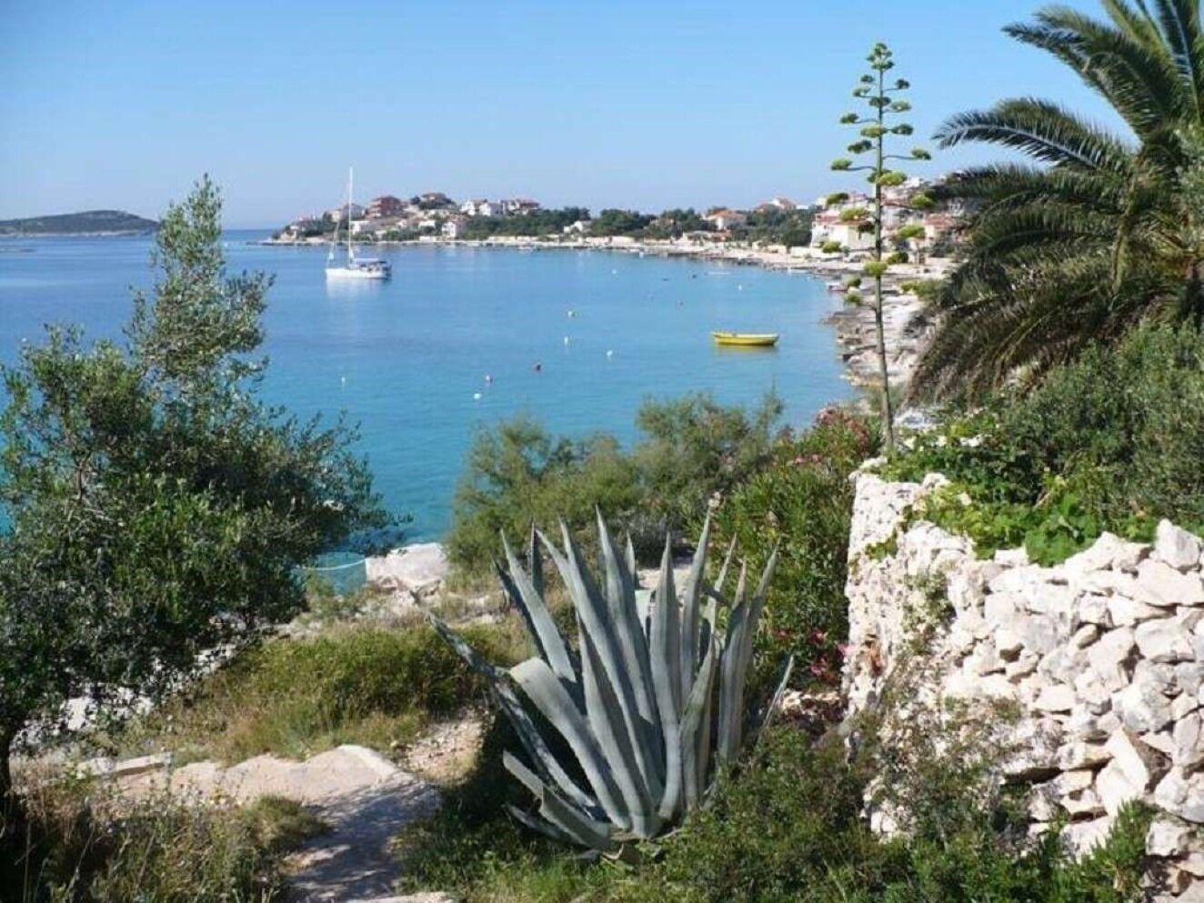 Blick auf die Küste, strahlend blauer Himmel, felsiges Ufer und einige Boote auf dem Wasser.
