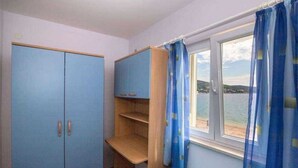 Une pièce dotée d’une grande armoire, d’un bureau en bois et d’une fenêtre avec des rideaux.