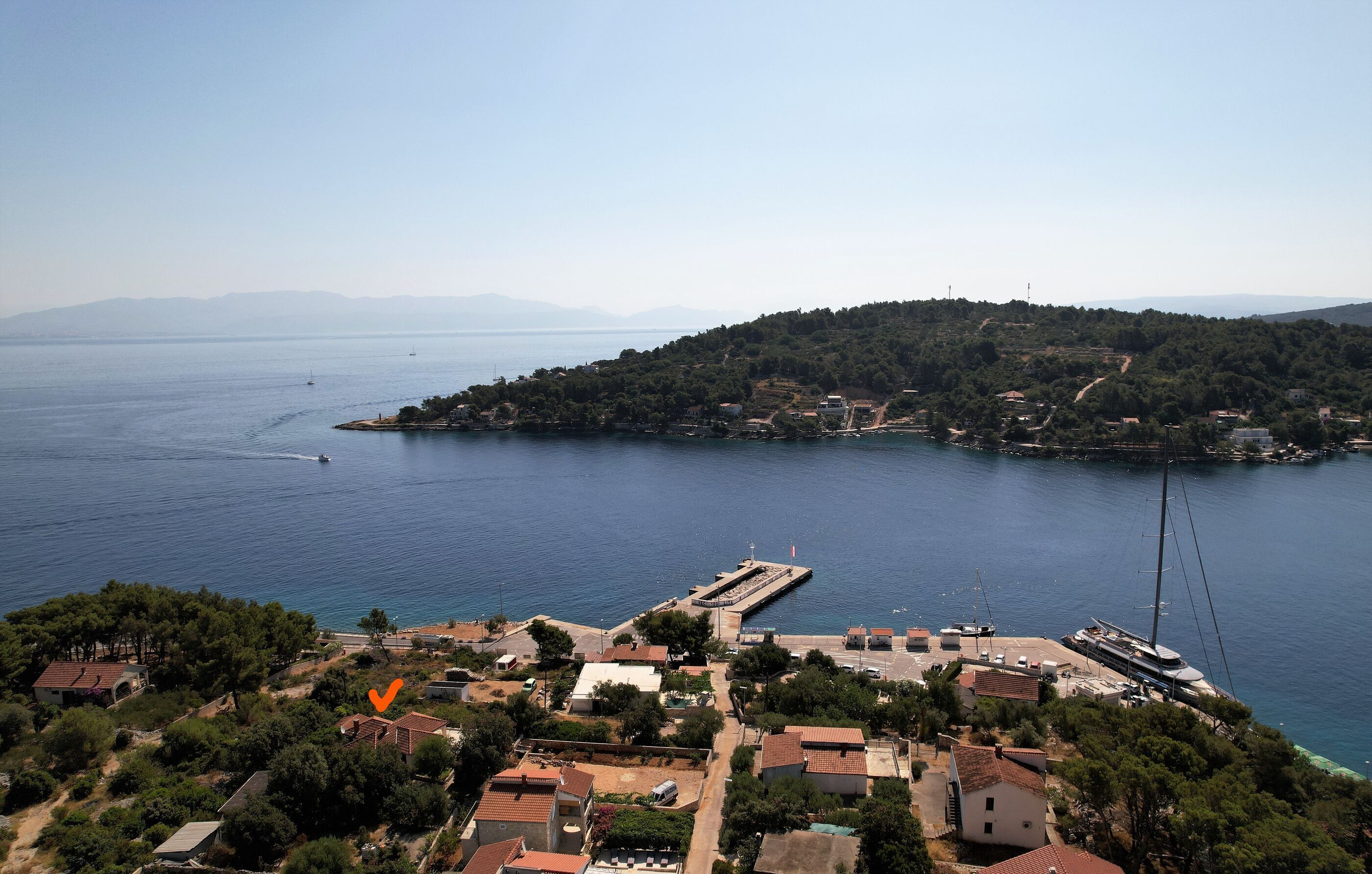 A coastal town with a marina, houses, and a hilly backdrop.
