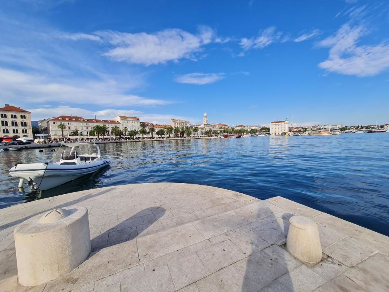 Vista al agua con un barco atracado, edificios a lo largo de la orilla y cielo despejado.