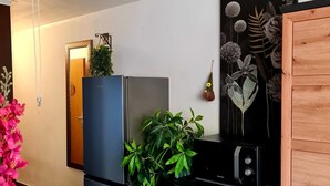 A compact kitchen with a refrigerator, stove, and wooden cabinet. - Apartment Lovely (Split)