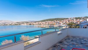 A terrace with a view of a coastal town, a pool, and a tiled floor. - Apartments Duga (Okrug)