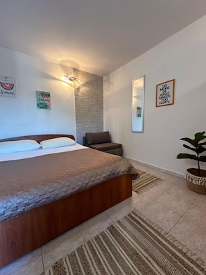 A bedroom with a bed, a chair, a potted plant, and wall decorations. - Apartments Ivana (Trpanj)