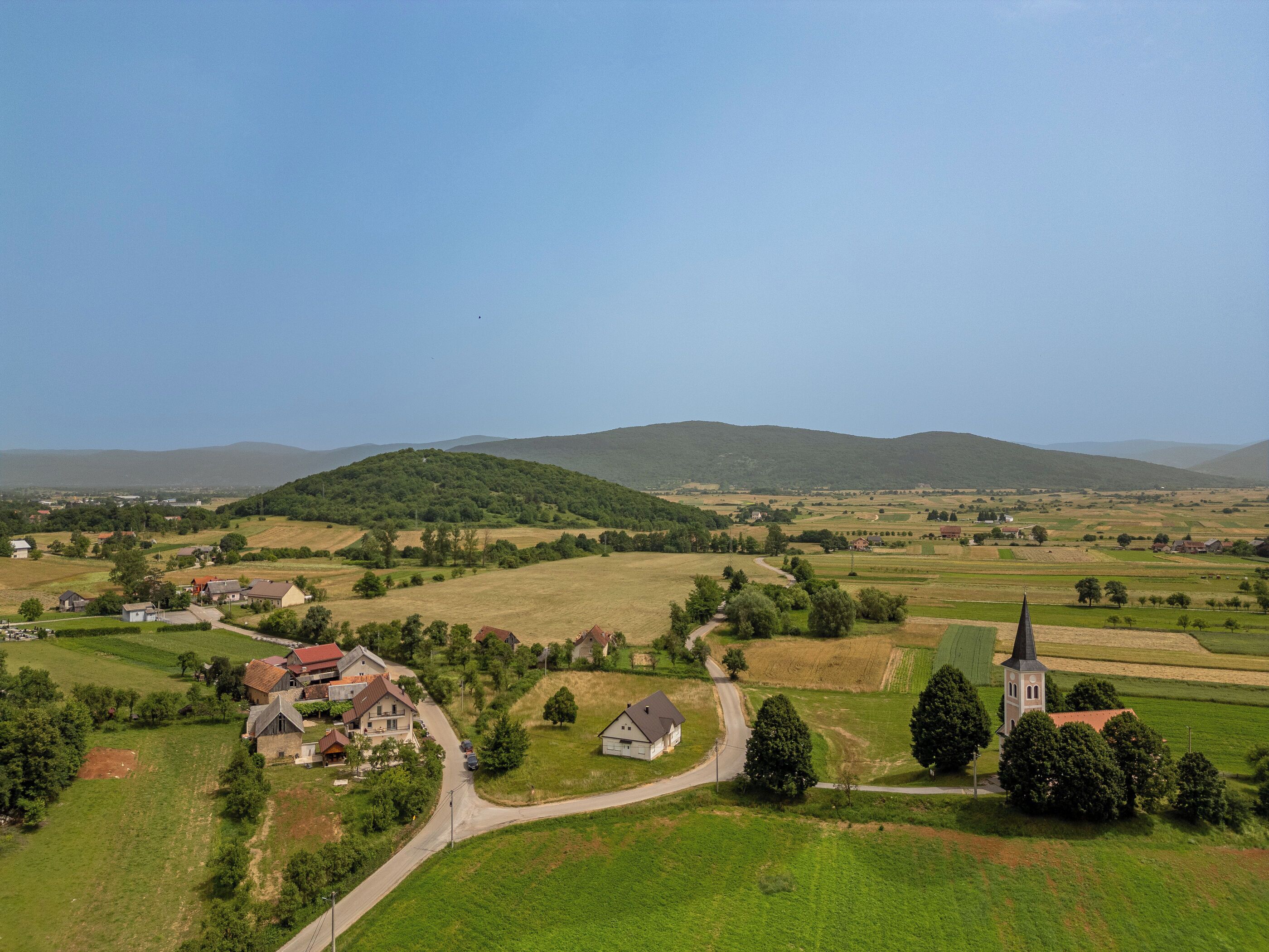 Paisagem rural com uma igreja, casas e campos.