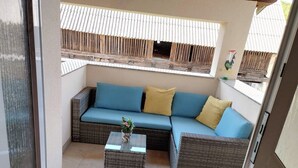 A balcony with a wicker sofa, a small table with a plant, and a potted plant. - House Rose (Otocac)