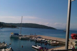 A marina with boats docked, a sandy beach, and a hilly landscape in the background. - Apartment Darina (Solta)