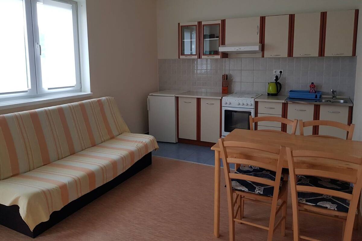 A compact kitchen with a built-in oven, a small refrigerator, and wooden cabinets.