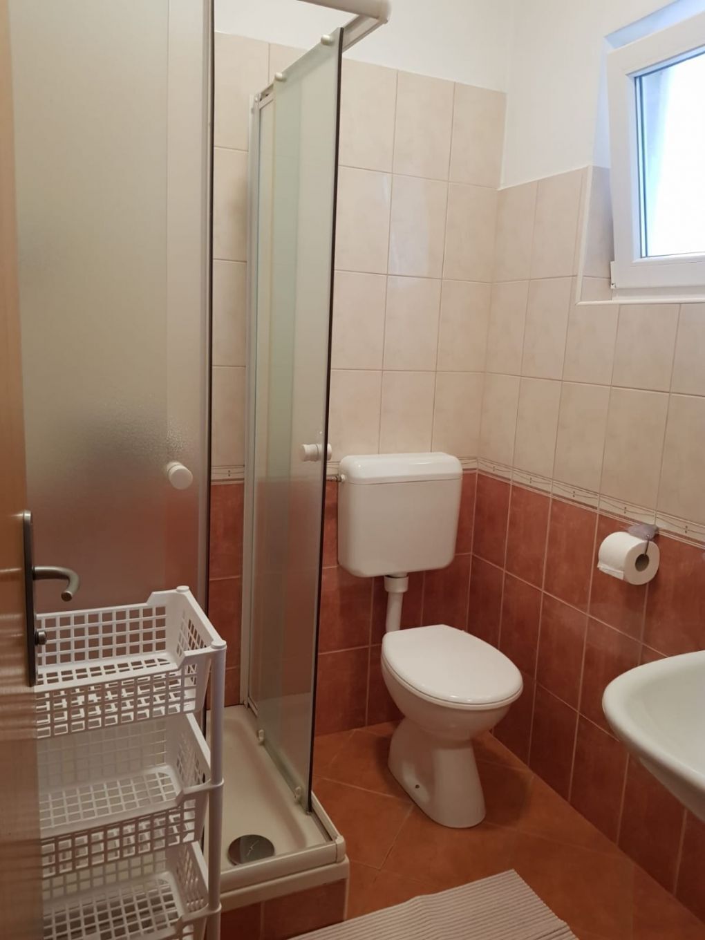 A bathroom with a glass shower enclosure, a toilet, and a sink.