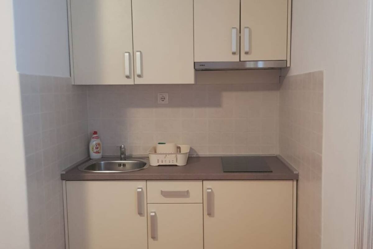 A small kitchenette with white cabinets, a stainless steel sink, and a countertop.