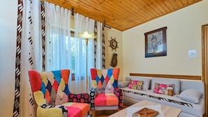 A cozy living room with two colorful armchairs, a sofa, and a wooden coffee table. - Apartment Giuseppe (Mali Losinj)